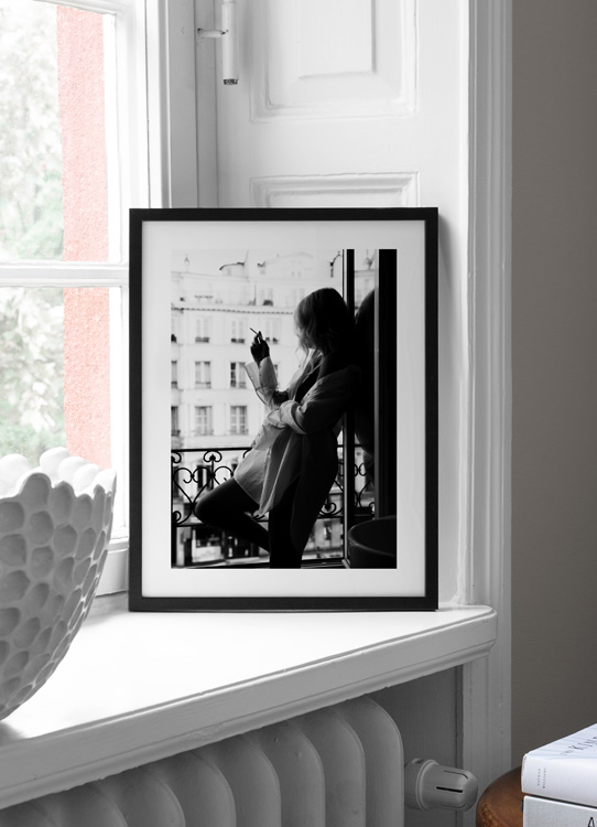  – Schwarz-weiß-Fotografie von einer Frau, die ein zu großes Hemd trägt und eine Zigarette in einem Fenster raucht