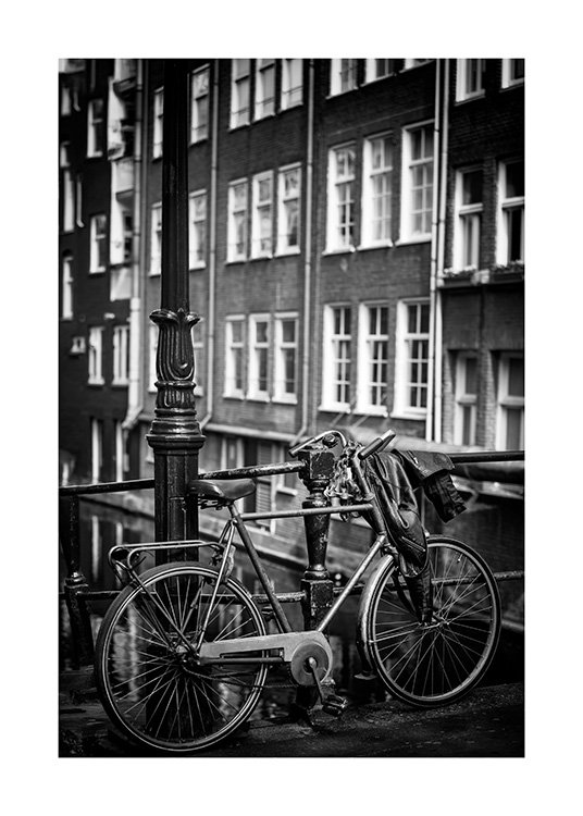  - Photographie en noir et blanc d'un lampadaire à côté d'un vélo garé et devant une maison avec fenêtres