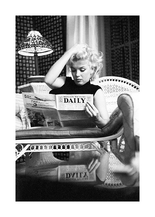  – Photographie en noir et blanc de l’icône Marilyn Monroe lisant un journal sur le canapé