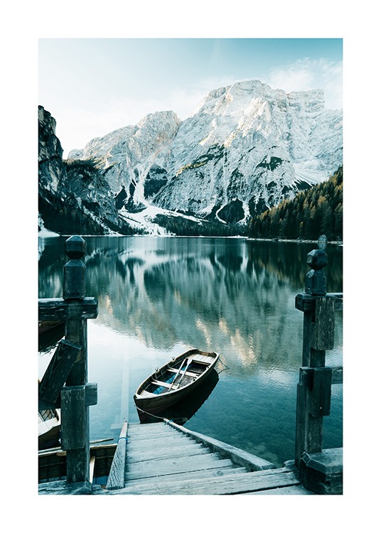  – Photographie de montagnes enneigées derrière un lac avec un bateau et un escalier en bois devant
