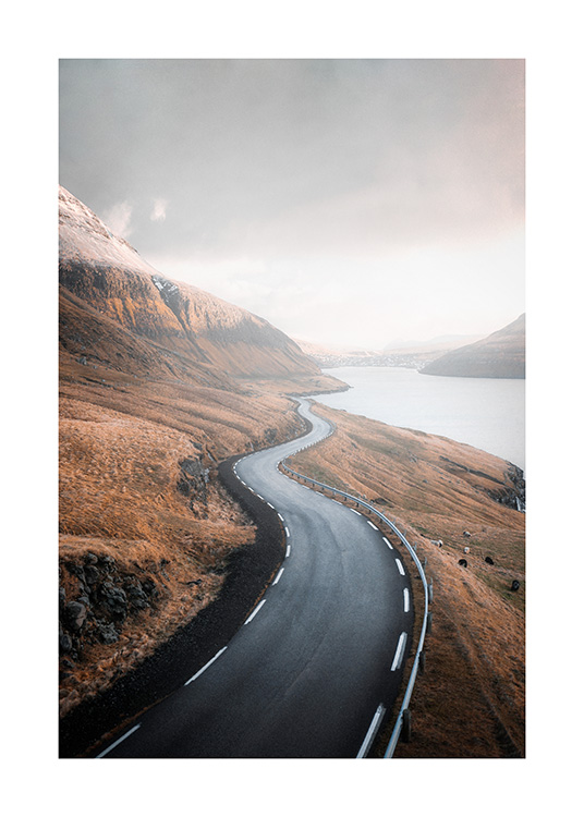  – Fotografie einer Berglandschaft, die in der Bildmitte von einer Straße durchzogen wird und rechter Hand einen See erkennen lässt