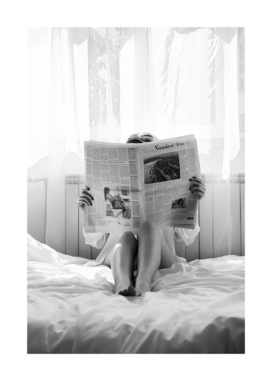  – Photographie en noir et blanc d’une femme lisant un journal dans son lit