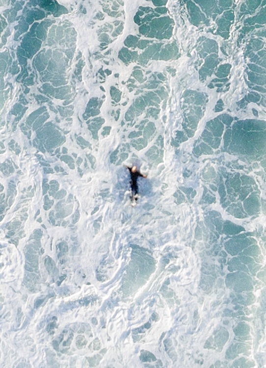  – Foto van bovenaf van een oceaan met grote golf die naar een surfer komt