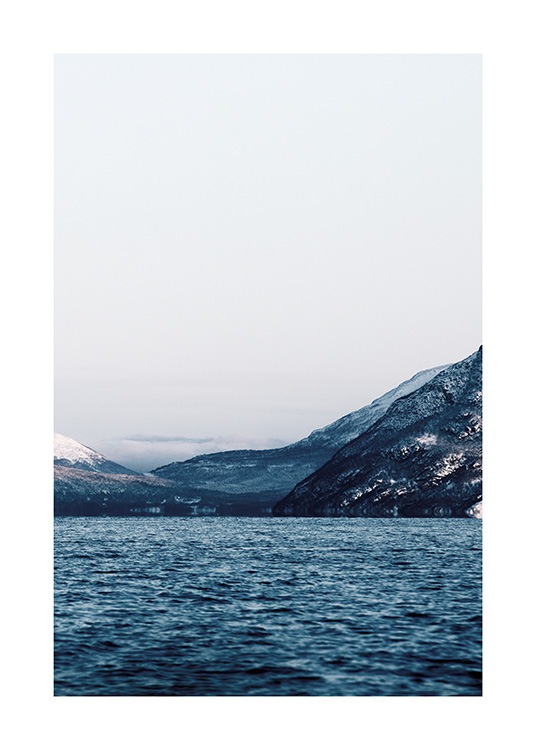  - Photographie d'un paysage montagneux avec un ciel bleu clair avec un océan au premier plan
